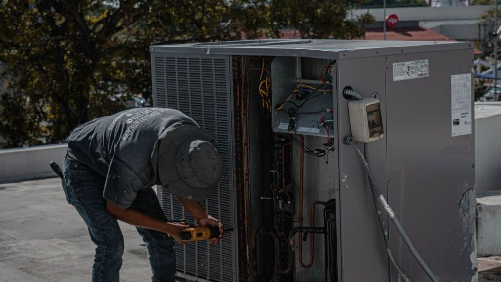 HVAC technician inspecting a rooftop air conditioning unit for AC system leak repair.