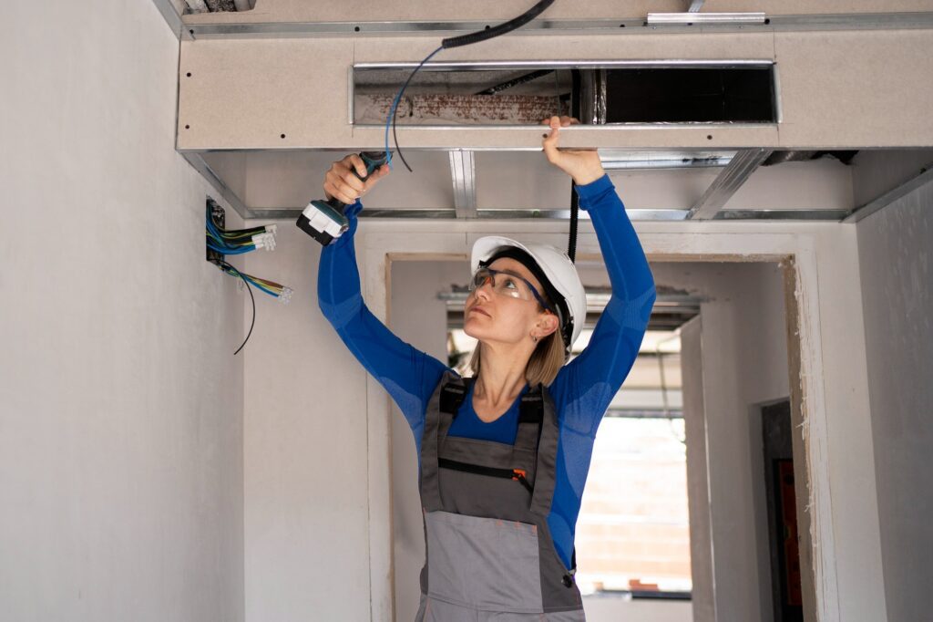 Female HVAC technician inspecting ductwork for air leaks, airflow problems, and damage.Â