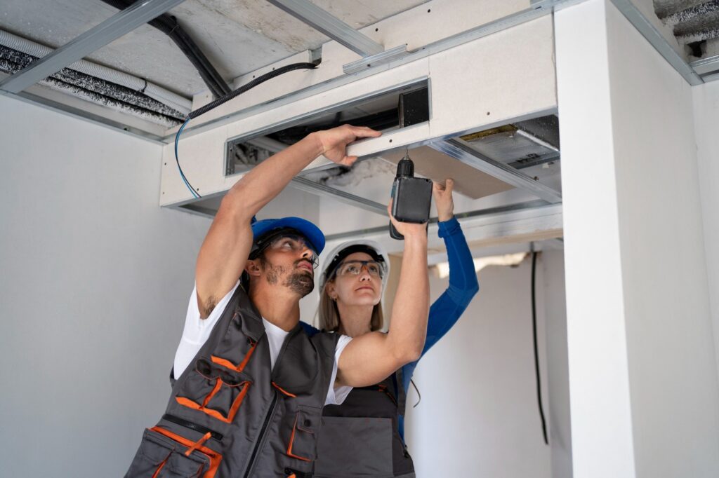HVAC technicians working on an AC duct repair inspection.