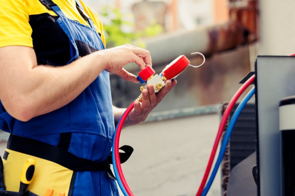 HVAC technician checking an air-conditioning compressor and checking its electrical components.