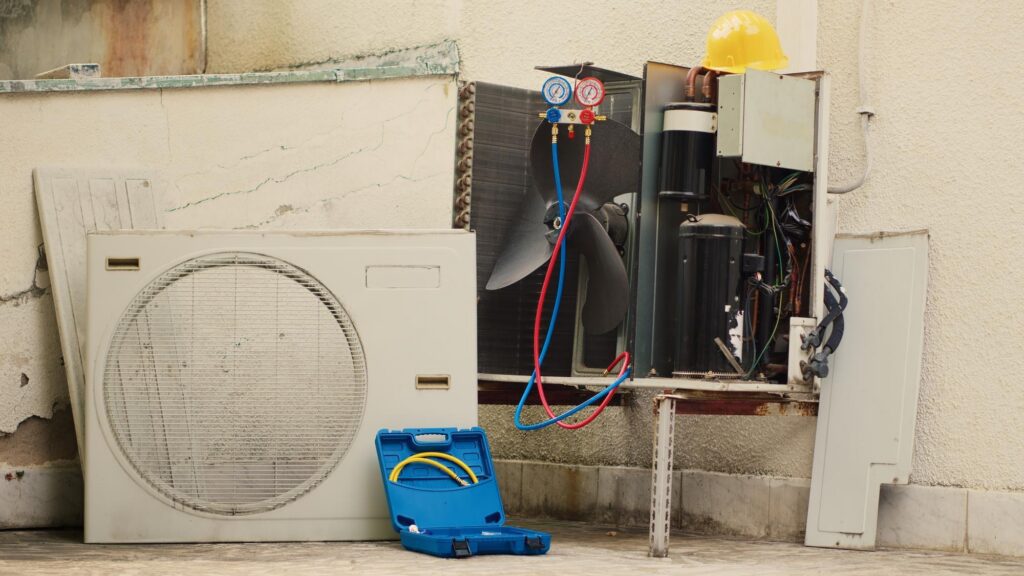 Open outdoor AC unit with gauges and exposed components.